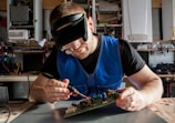a man wearing a blindfold working on a circuit board