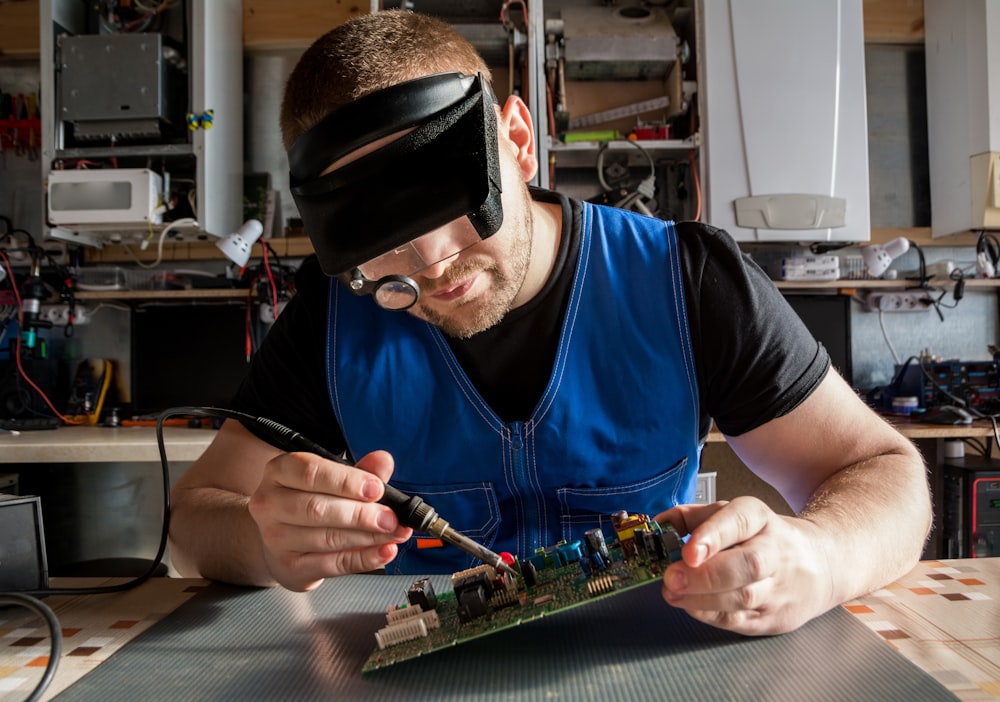 a man wearing a blindfold working on a circuit board