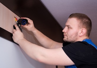 a man working on a wall with a screwdriver