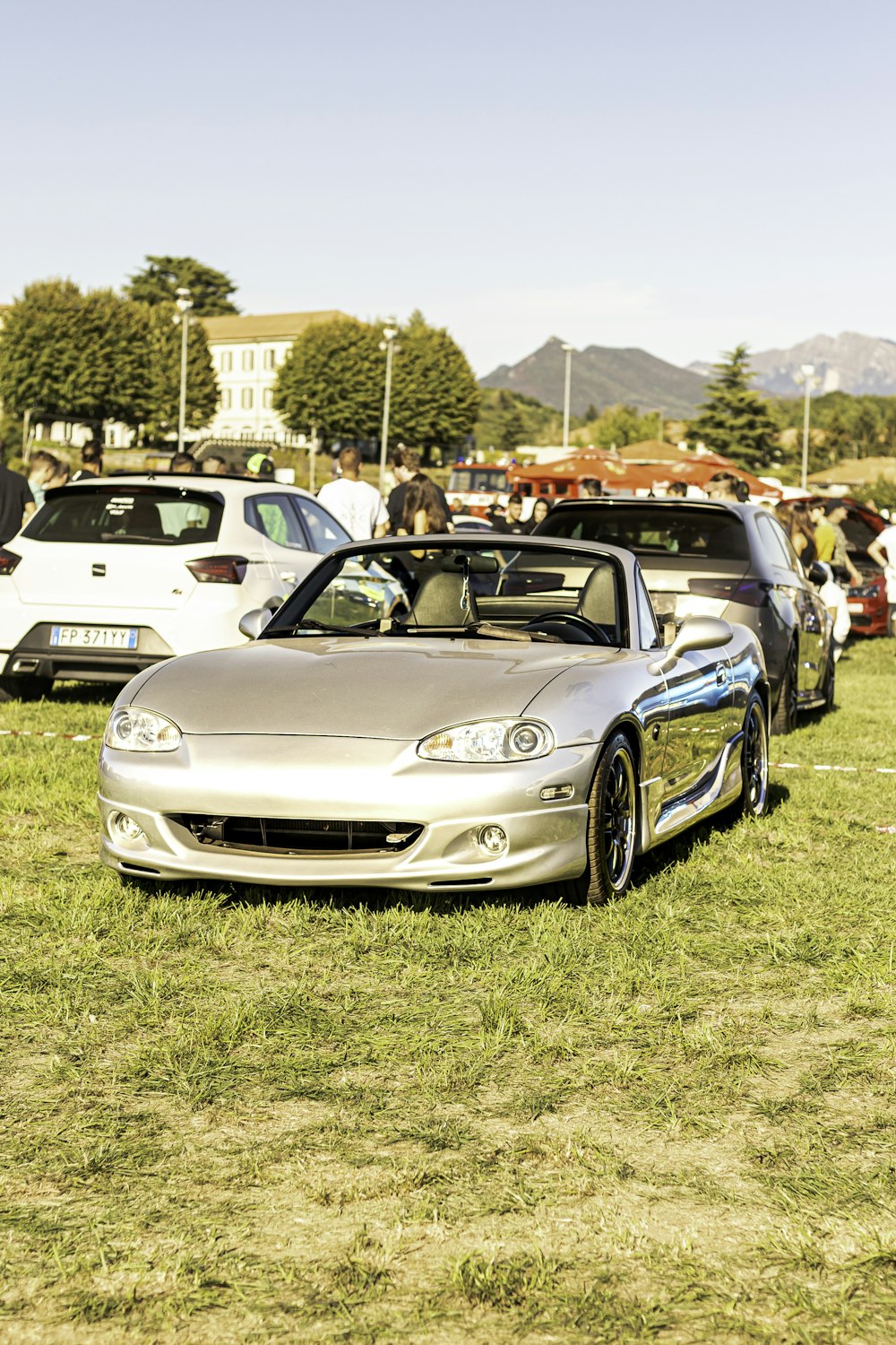 a group of cars parked on top of a grass covered field