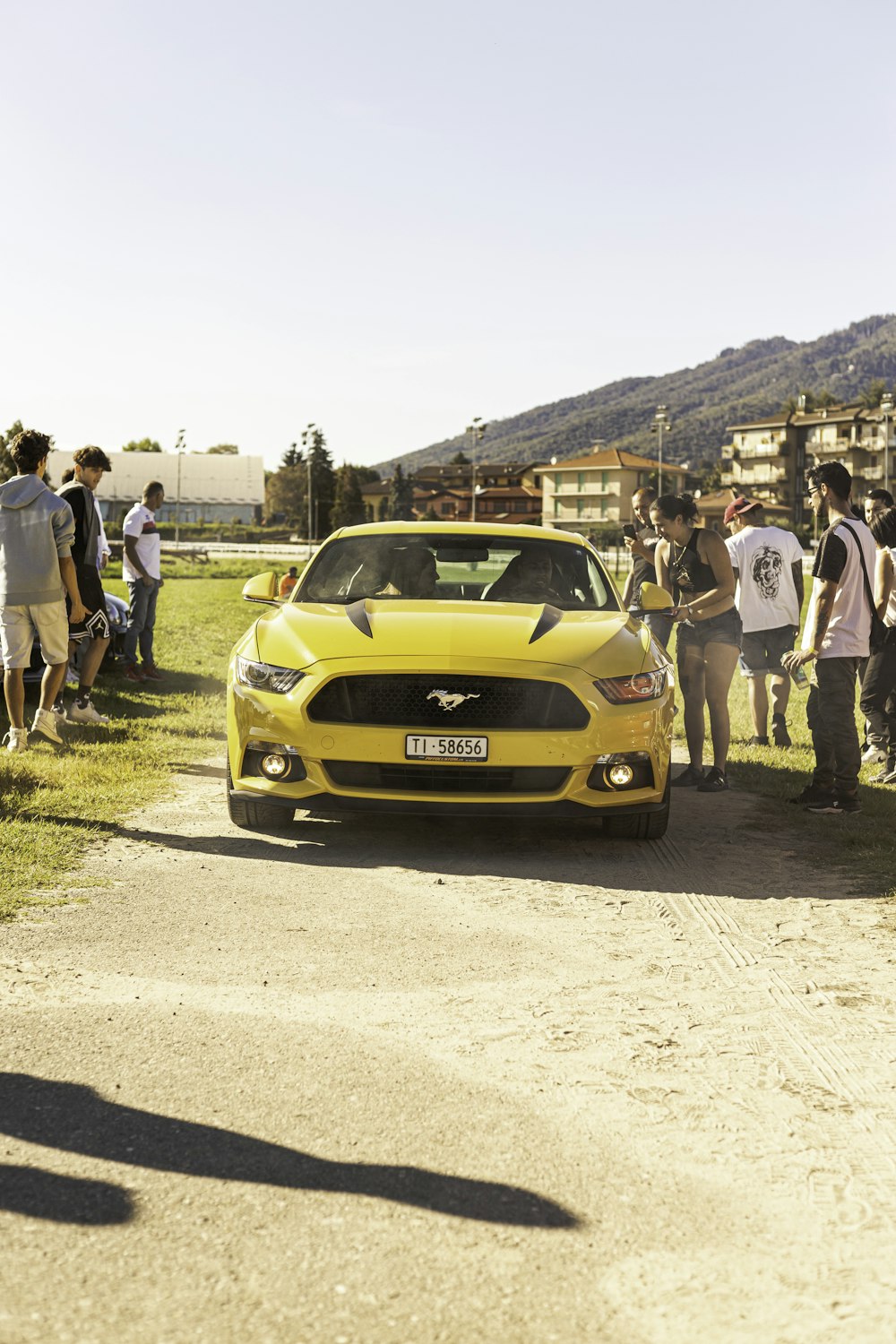 a group of people standing around a yellow car