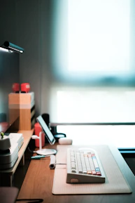 Close-up of hands typing on a keyboard with a bright, minimalist desk setup.