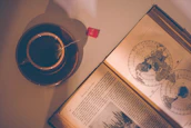 A smiling senior enjoying a Nostalgia Puzzles book at a kitchen table with a cup of tea.