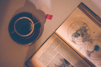A cozy vintage suitcase with travel stickers, sitting beside a steaming cup of tea by a window.