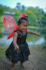 A joyful child wearing handmade paper wings smiling in a sunny park.