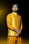 Intricate patterns on a mustard yellow kurta highlighted by soft natural lighting.