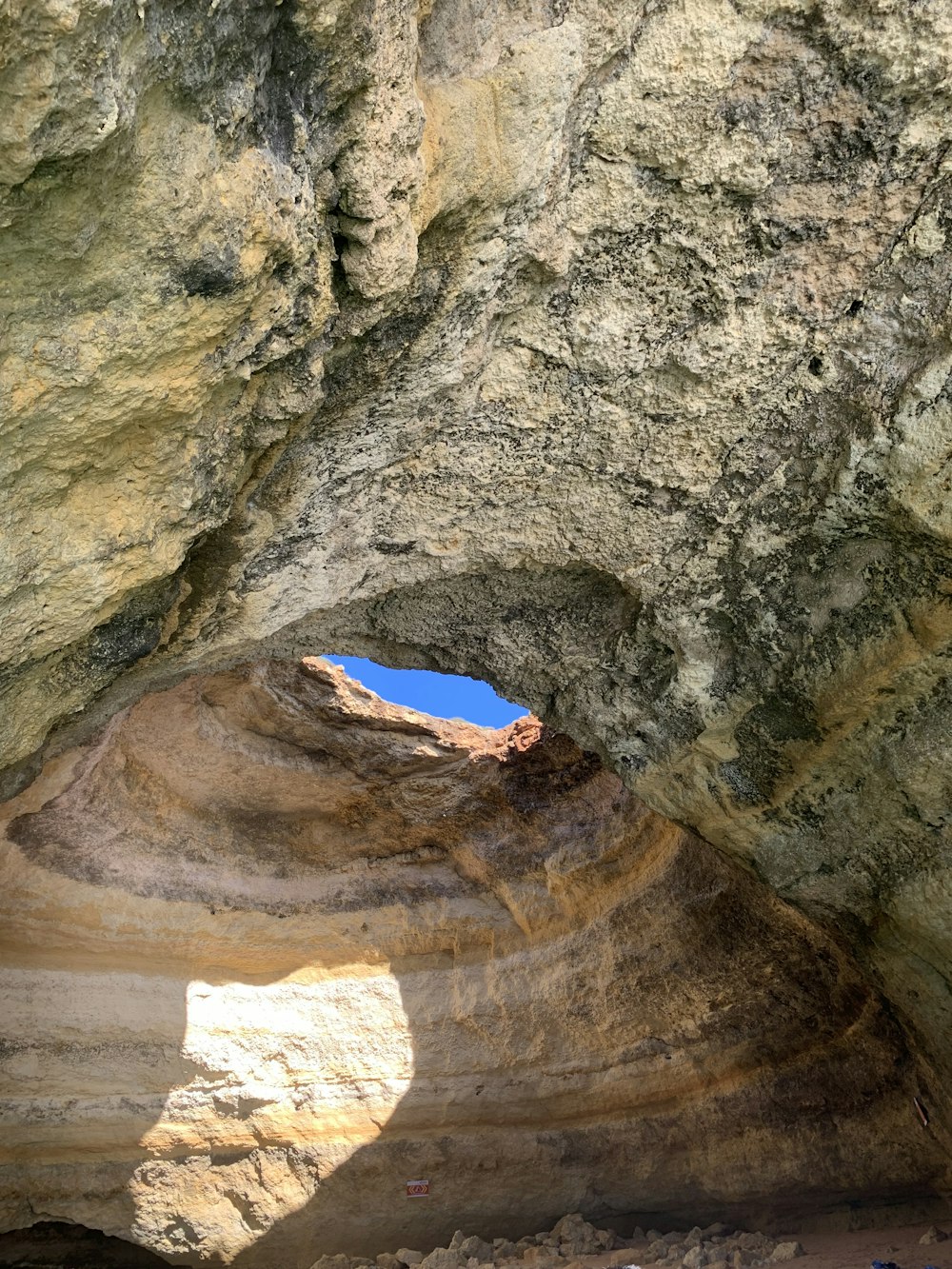 Una persona parada en una cueva con un cielo azul en el fondo