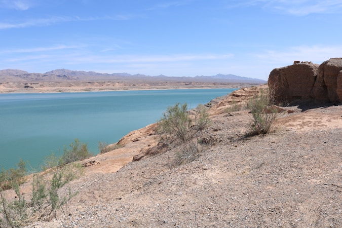 Lake Mead water against a steep rocky cliff with a pale mineral bathtub ring above the current waterline
