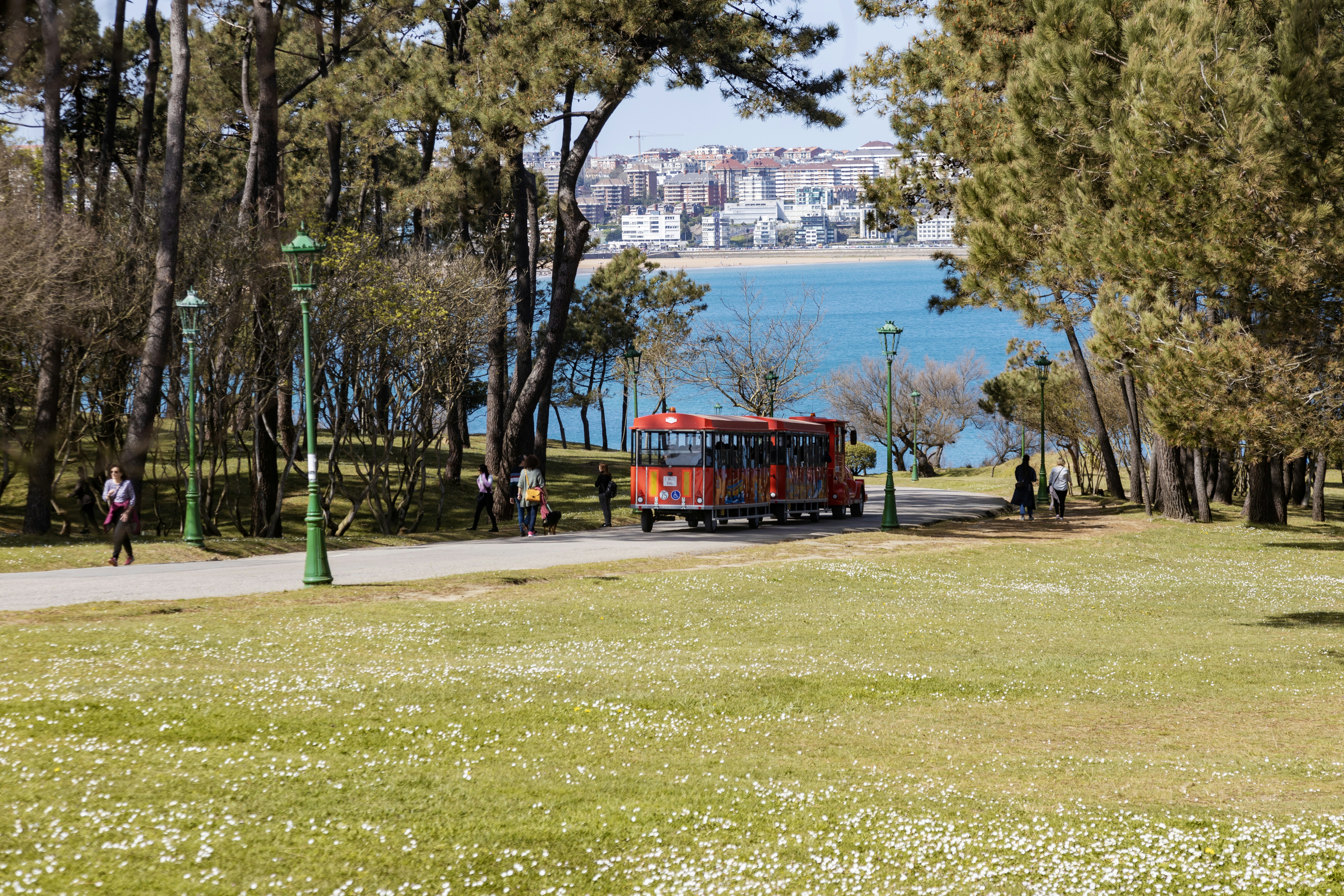 a red truck driving down a road next to a park, 