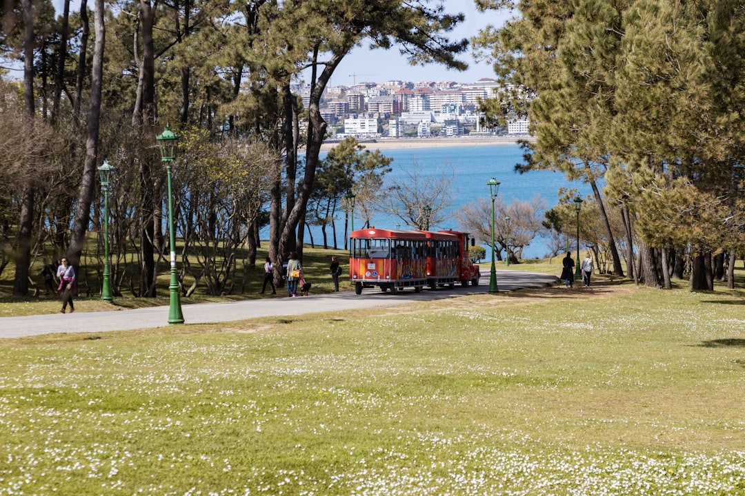 a red truck driving down a road next to a park,
