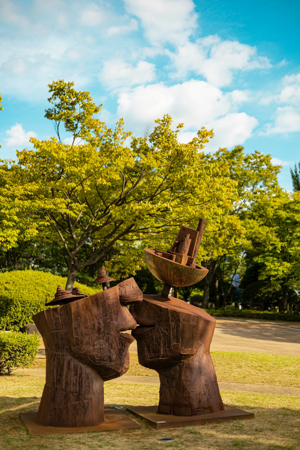 a couple of wooden sculptures sitting on top of a lush green field
