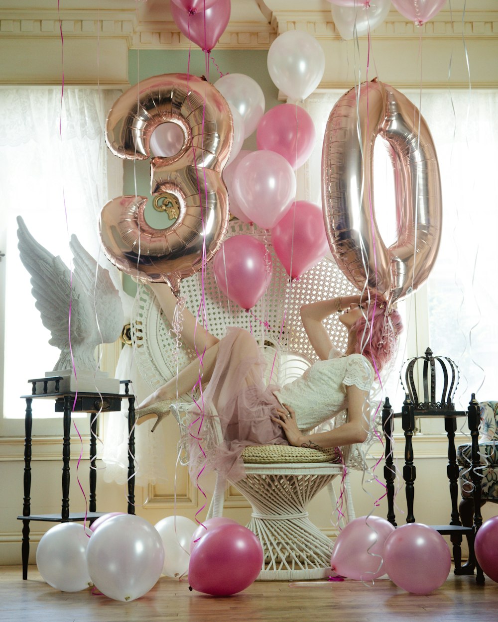 a woman laying on a chair surrounded by balloons