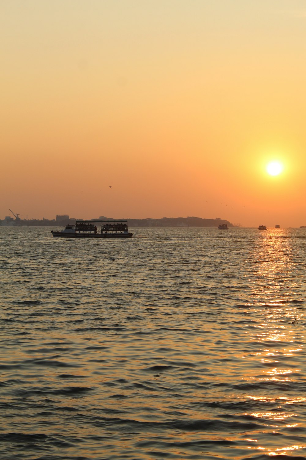 a sunset over a body of water with a boat in the distance