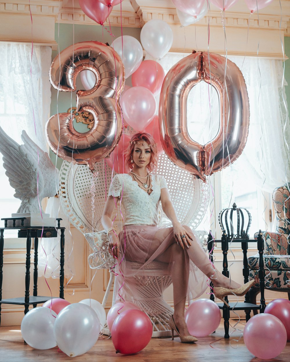 a woman sitting on a chair surrounded by balloons