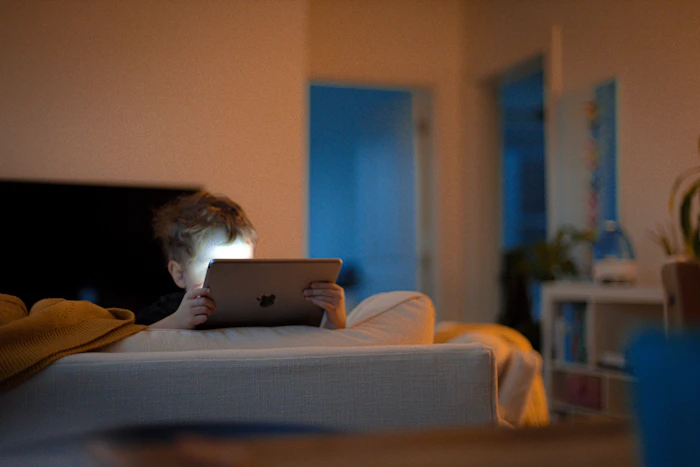 Kid using a tablet on the couch at home