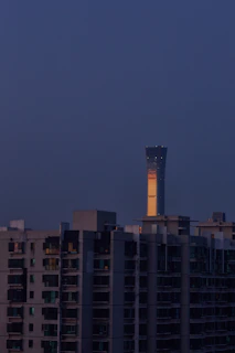 A high-rise residential building listed on the Chemmanur Properties auction platform, bathed in warm evening light.