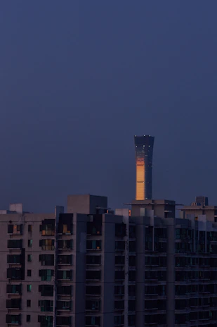 A high-rise residential building listed on the Chemmanur Properties auction platform, bathed in warm evening light.
