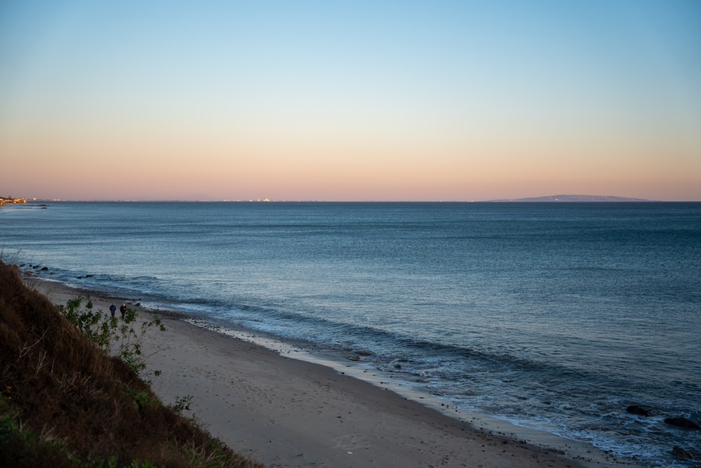a view of a beach at sunset with the ocean in the background