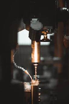 A close-up of a worker operating a core cutting machine, sparks flying against dramatic industrial lighting.
