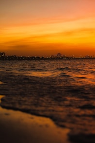 a sunset view of the ocean with a city in the distance