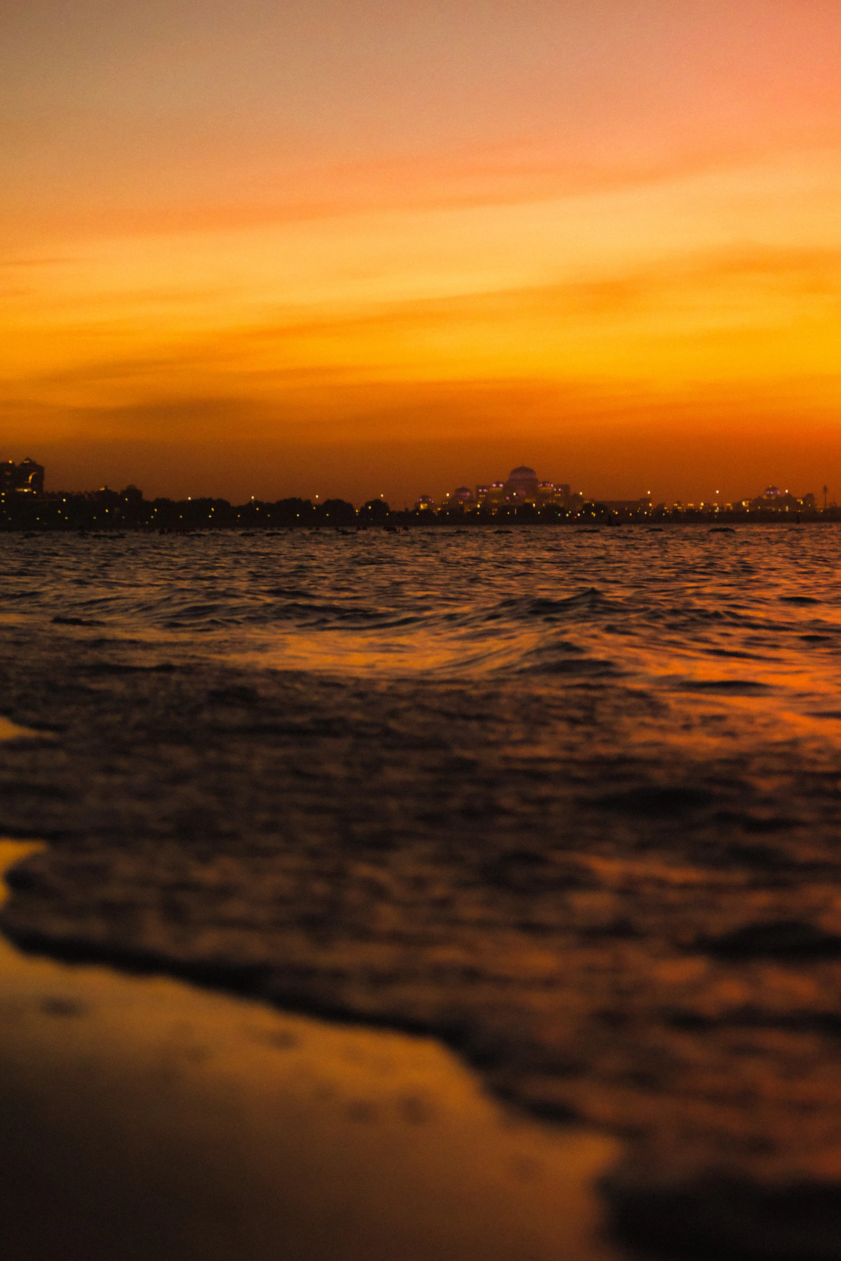 The Abu Dhabi Corniche and distant skyline beneath a glowing sunset sky
