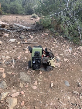 A large RC truck climbing a rocky hill surrounded by dirt and greenery.