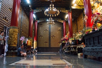 A group of community members gathered in prayer inside the temple, surrounded by golden accents and traditional decor.