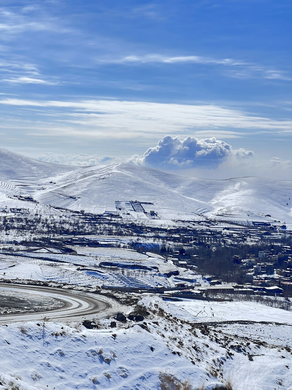 a snowy landscape with a road and mountains in the background