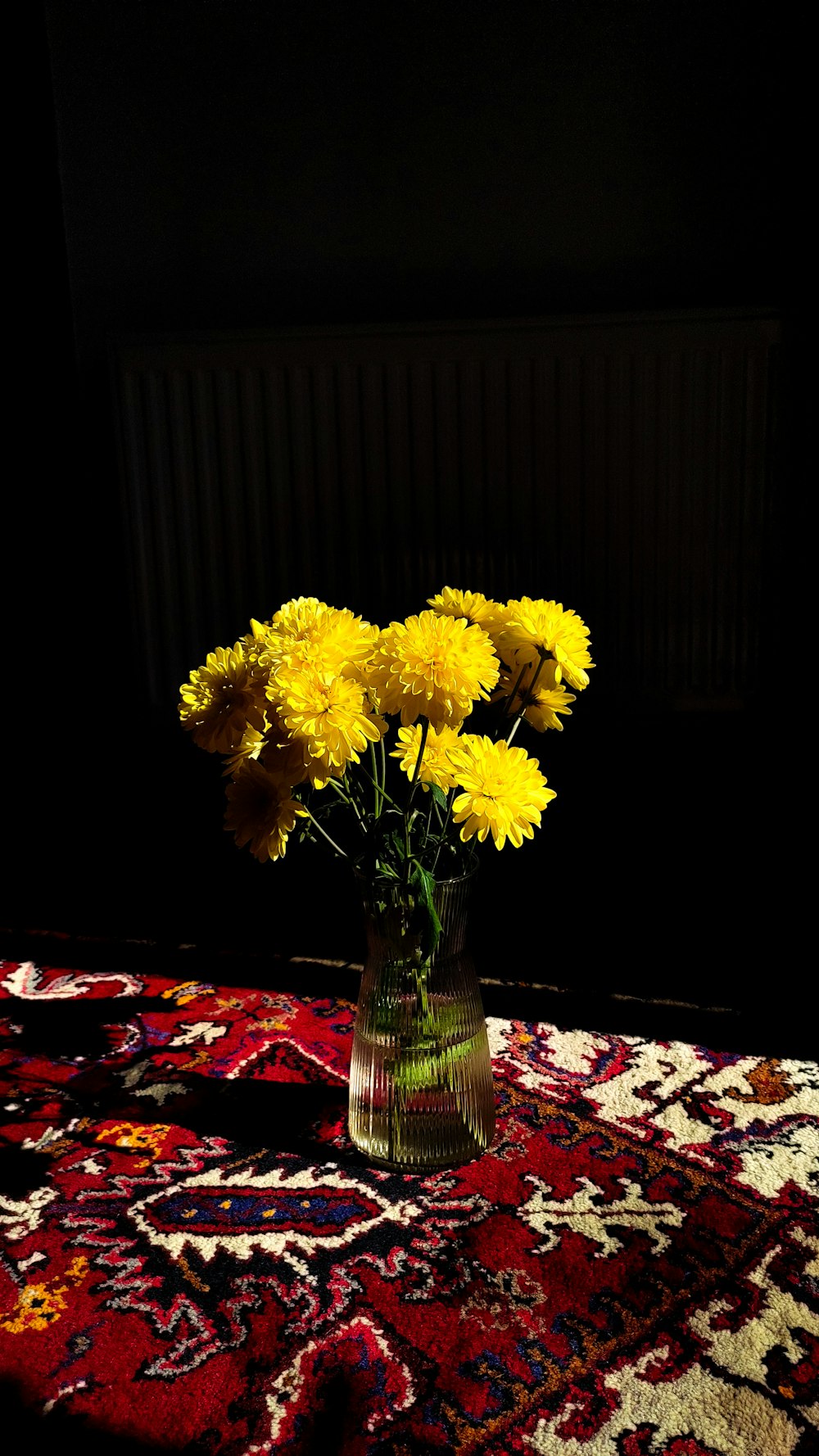 a vase filled with yellow flowers on top of a rug