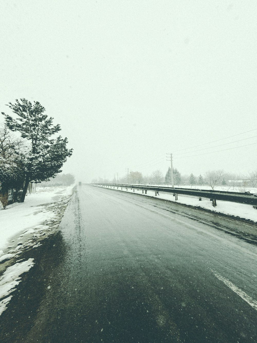 a road with snow on the ground and trees on the side