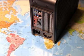A map of the world overlaid with a computer network device, possibly a server or NAS, is stationed on top, partially covering South America and the Atlantic Ocean.