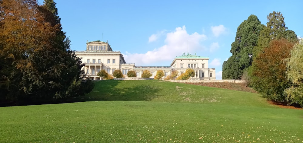 a large white building sitting on top of a lush green field