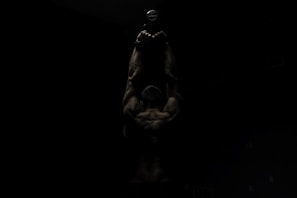Athlete gripping a heavy dumbbell mid-curl, muscles flexed under gym lights