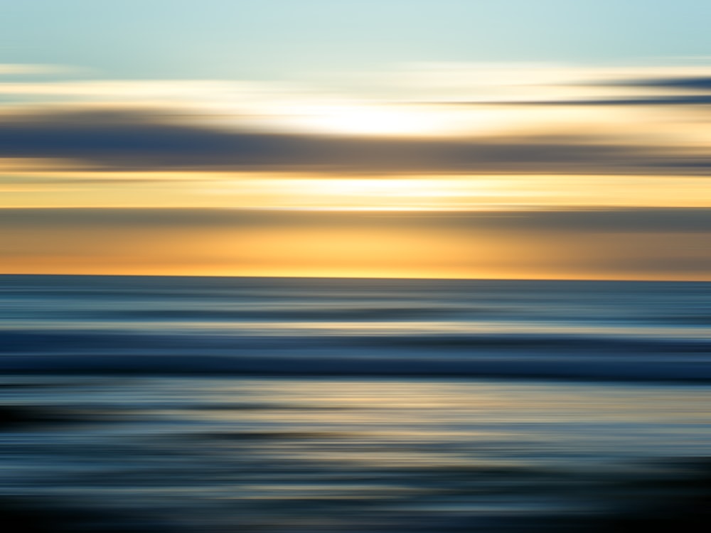 a blurry photo of the sun setting over the ocean