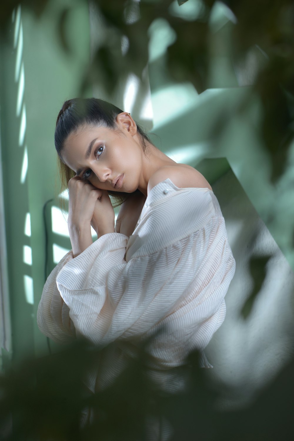 a woman in a white top leaning against a wall