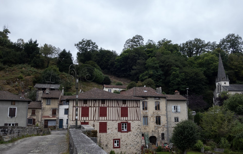 un vieux bâtiment aux volets rouges et un clocher en arrière-plan