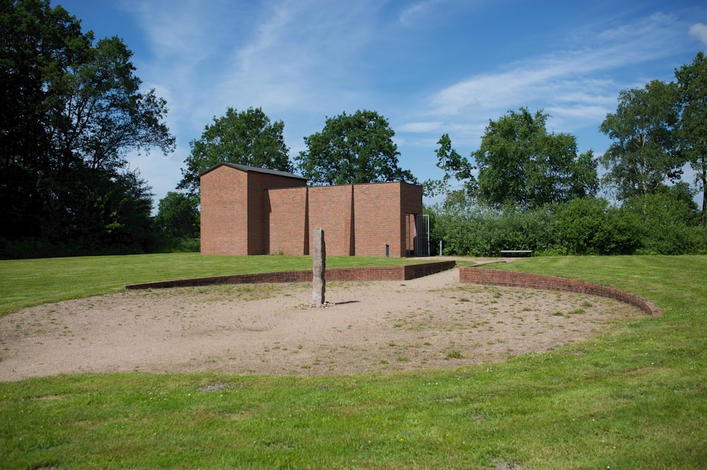 a building in a field with grass and trees in the background