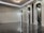 A sleek and modern interior space with polished marble floors and a high ceiling. The room features three tall, arch-shaped panels with decorative lighting and a subtle texture on the walls. A unique ceiling light fixture hangs centrally, adding an elegant touch.