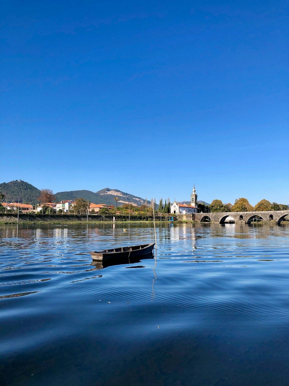 a boat floating on top of a lake next to a bridge