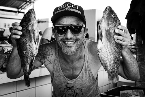 A smiling survivor holding a fish at the market.