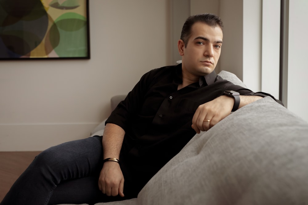 a man sitting on top of a couch next to a window