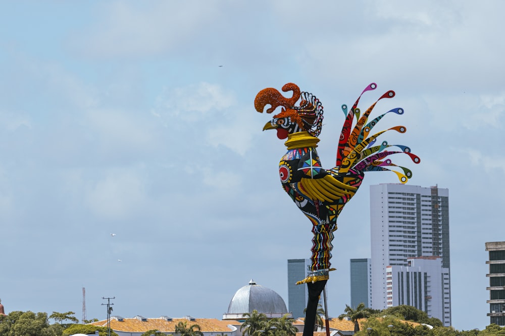 a statue of a rooster in front of a city skyline