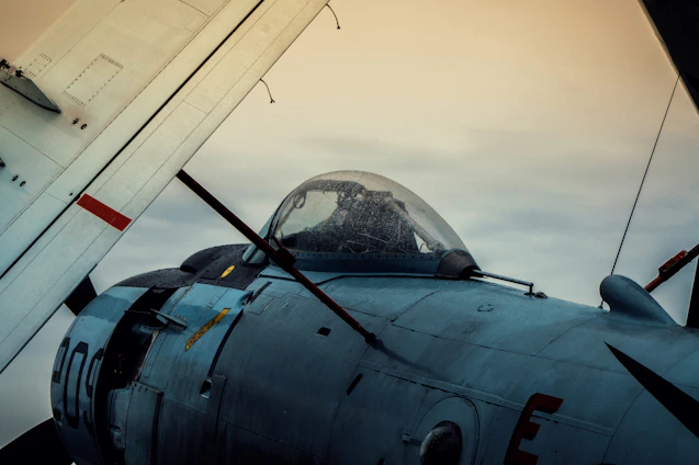 A seasoned pilot in flight gear inspecting an advanced military aircraft on the tarmac at sunrise.