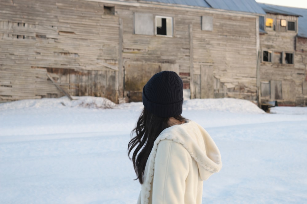 a woman standing in the snow in front of a building