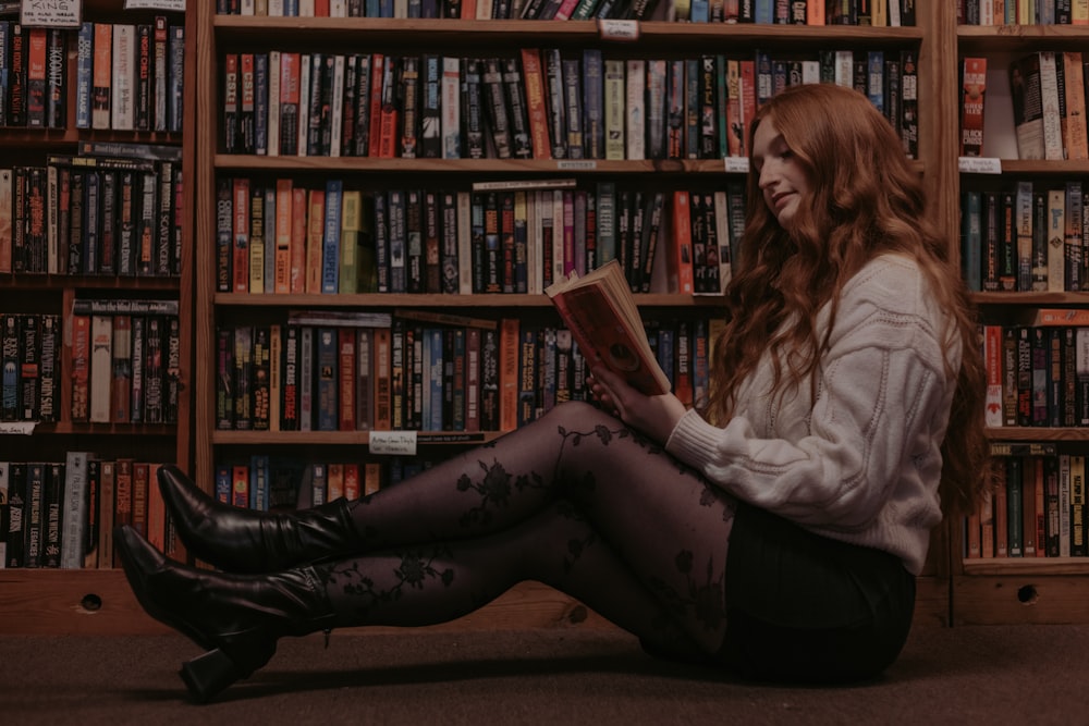 a woman sitting on the floor reading a book