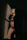 A person is standing in a dimly lit room, wearing black lingerie and a dark robe. The light casts a sharp geometric shadow on the wall, creating a dramatic and intimate atmosphere.