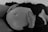 A person wearing a lace bra lies down with hands gently placed on a pregnant belly. The focus is on the peaceful and intimate moment captured in a black and white photograph.