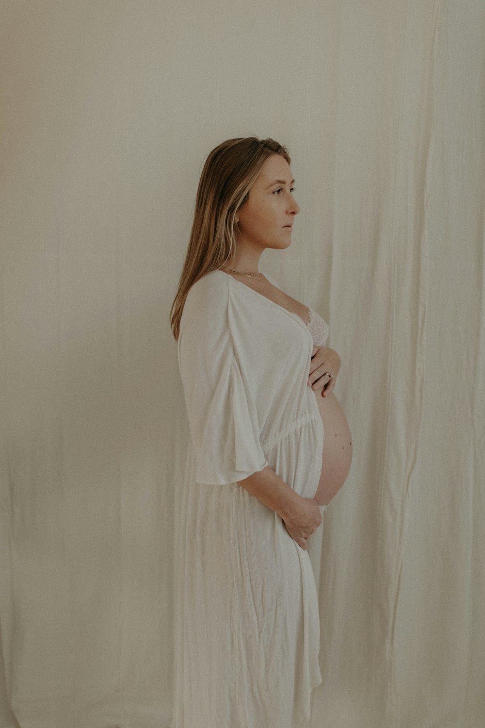 a pregnant woman standing in front of a white backdrop