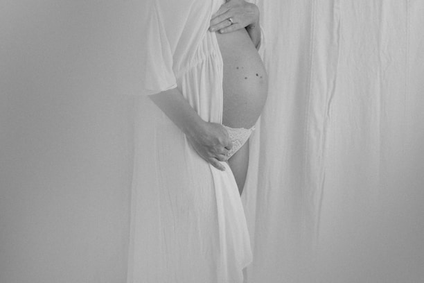 A serene, softly lit photo of a doula gently holding an expecting mother's hand.