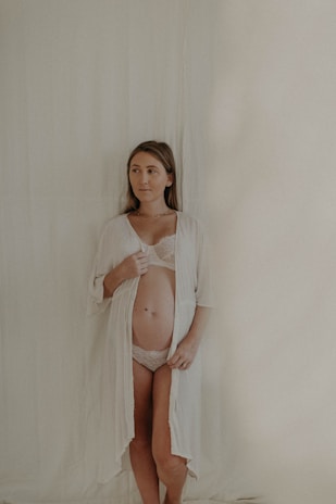 A lifestyle shot of a woman smiling while adjusting her sleekline shapewear in front of a mirror, radiating comfort and elegance.